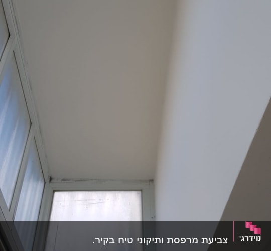חלון זכוכית עם מסגרת לבנה וקיר לבן